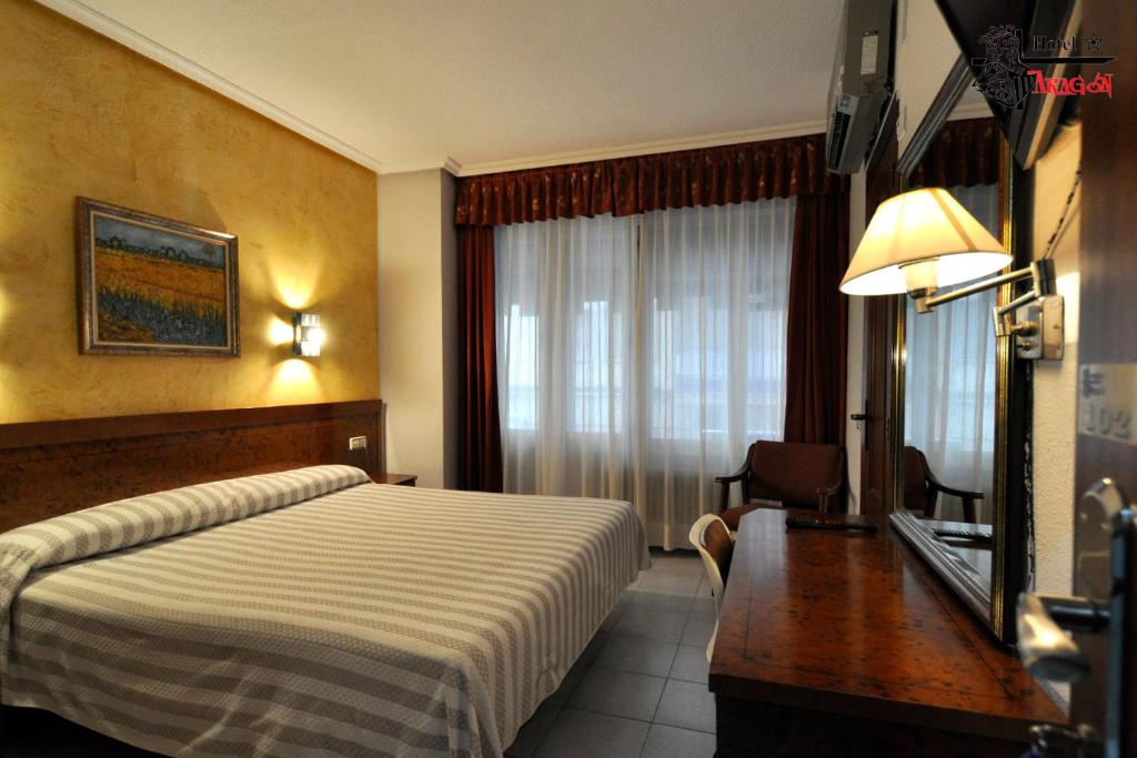 萨拉曼卡阿拉贡酒店的配有一张床、一张书桌和一扇窗户的酒店客房