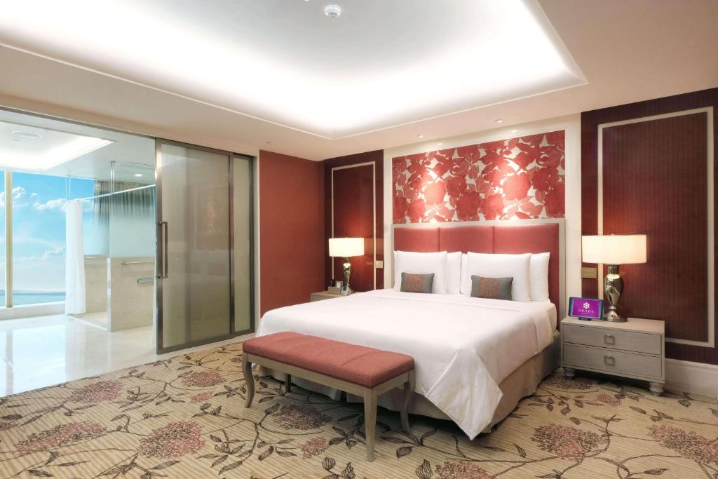 马尼拉Okada Manila的一间卧室设有一张大床和一个步入式淋浴间。