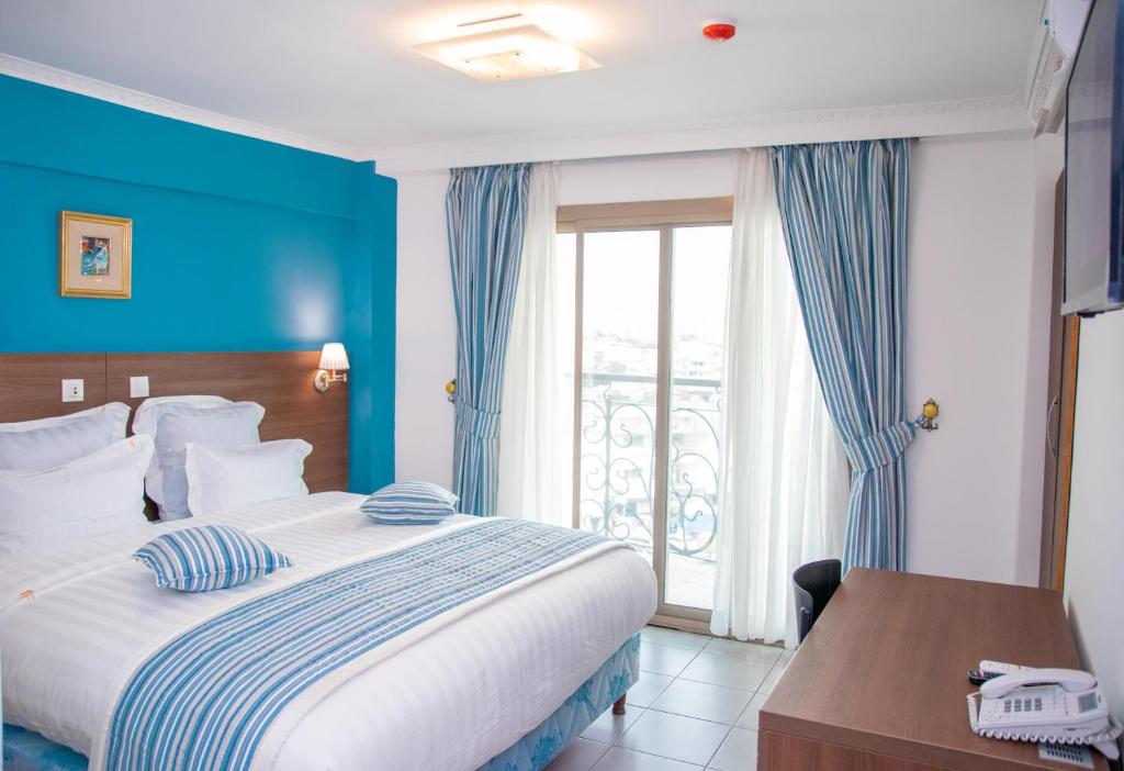杜阿拉FAYA Hotel的一间卧室配有一张蓝色墙壁的床和一扇窗户
