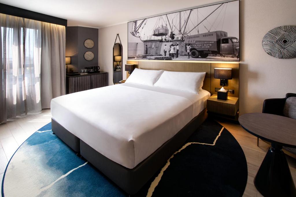 杜阿拉K Hotel Douala的卧室配有一张白色的大床和一张桌子