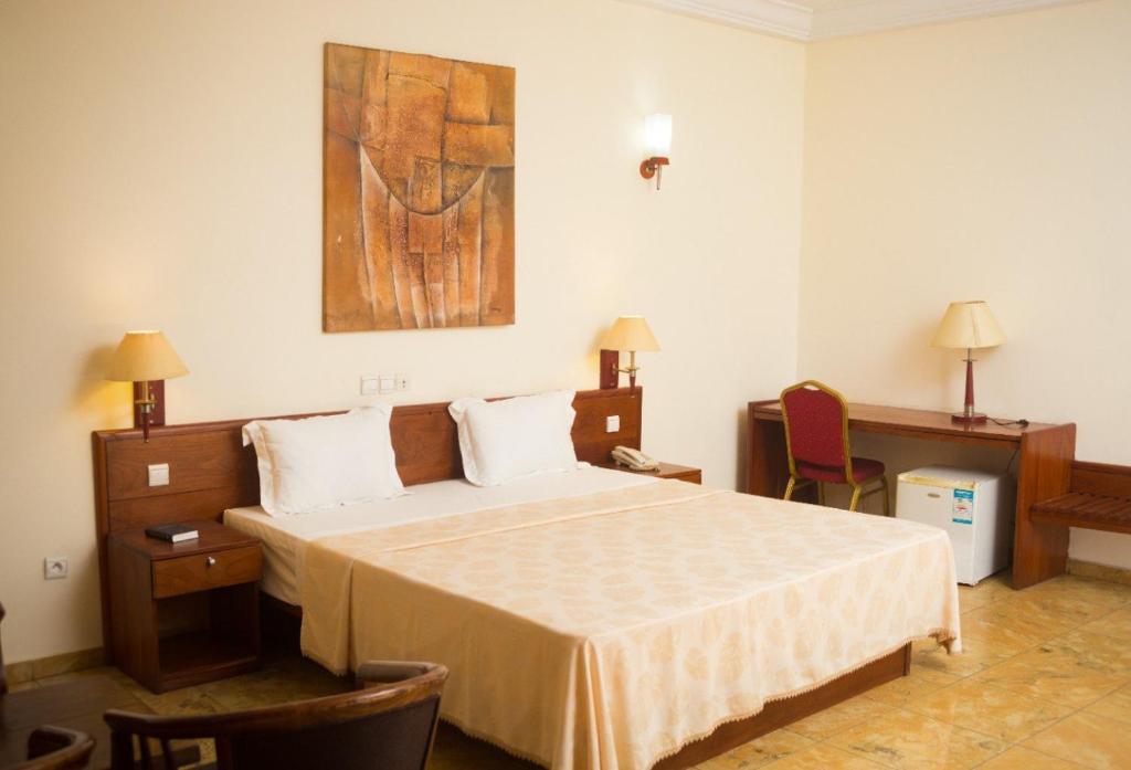 洛美Hôtel Marbella的卧室配有一张床,墙上挂有绘画作品