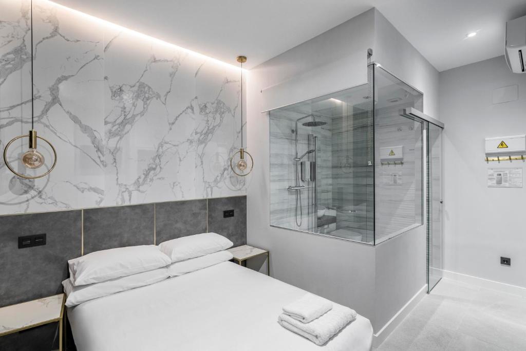 马德里EMBA ROOM的卧室配有白色的床和玻璃淋浴间