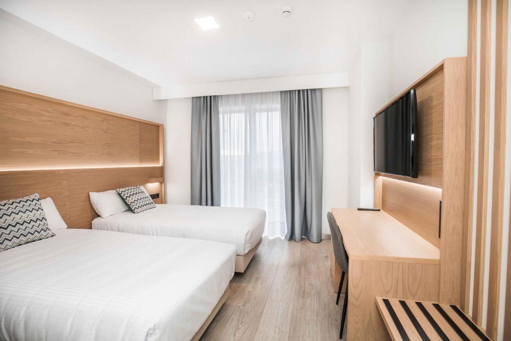 阿维拉Hotel Ciudad de Ávila的酒店客房设有两张床和一台平面电视。