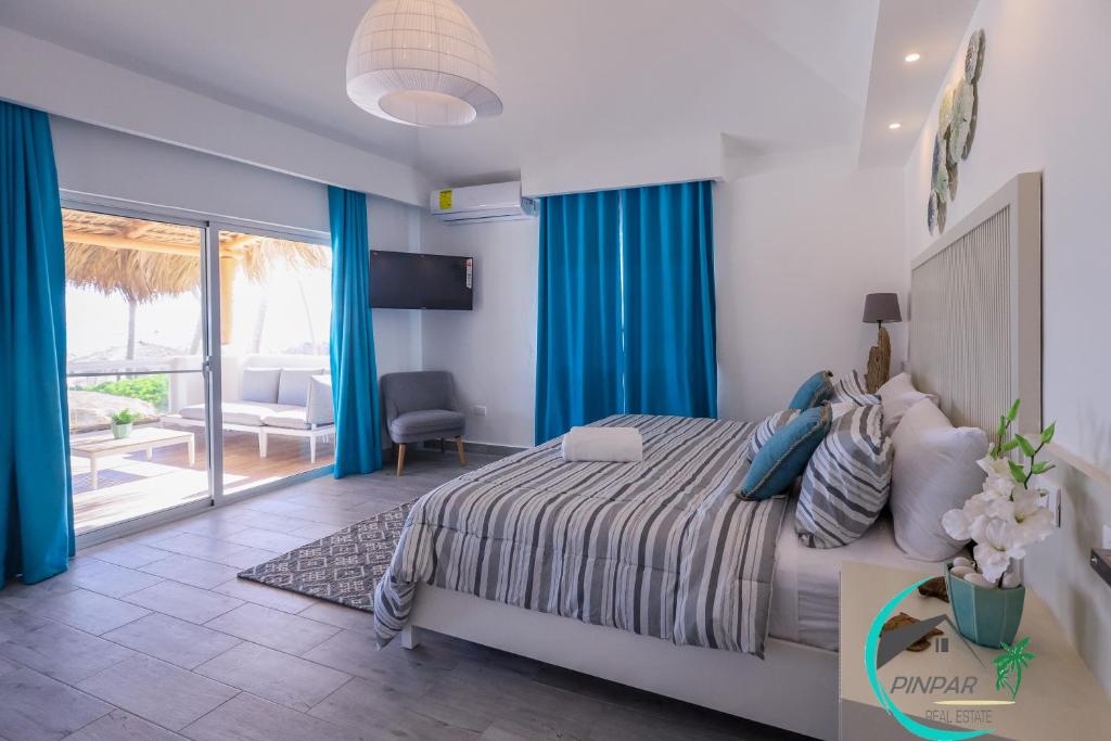 蓬塔卡纳Villa Blanca Beach Club的一间卧室配有一张蓝色窗帘的床和一个阳台