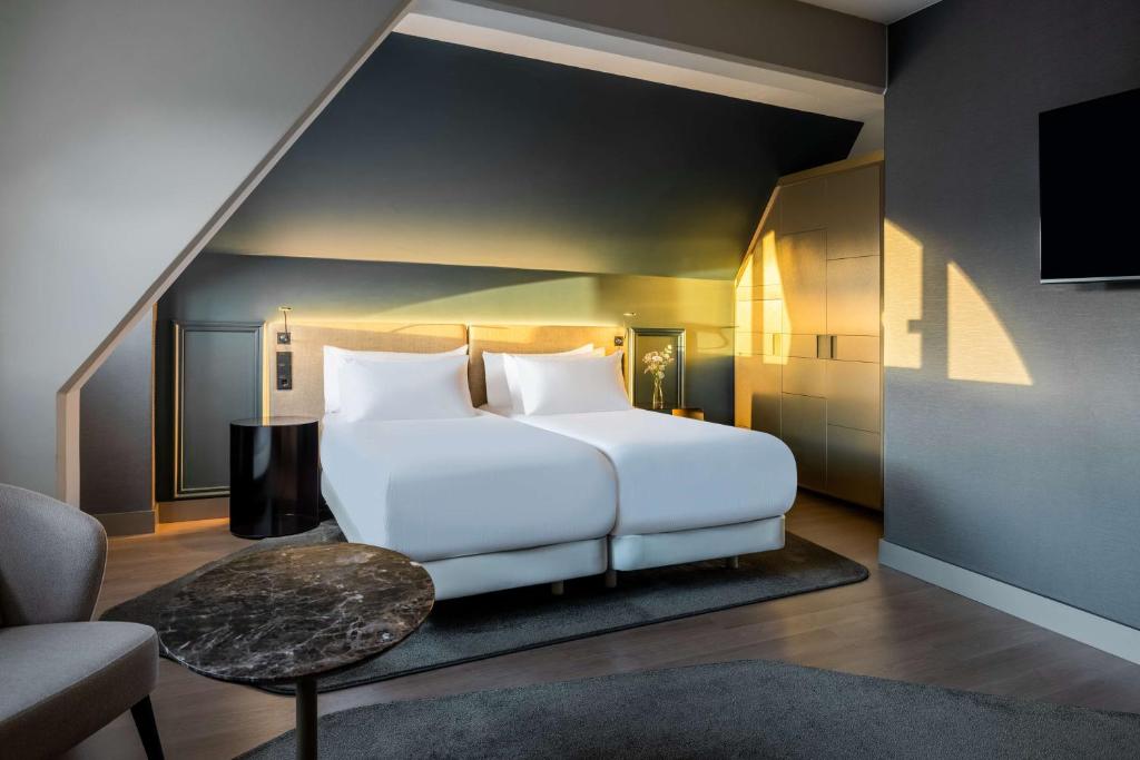 萨尔茨堡NH Collection Salzburg City的卧室配有一张白色大床和一把椅子