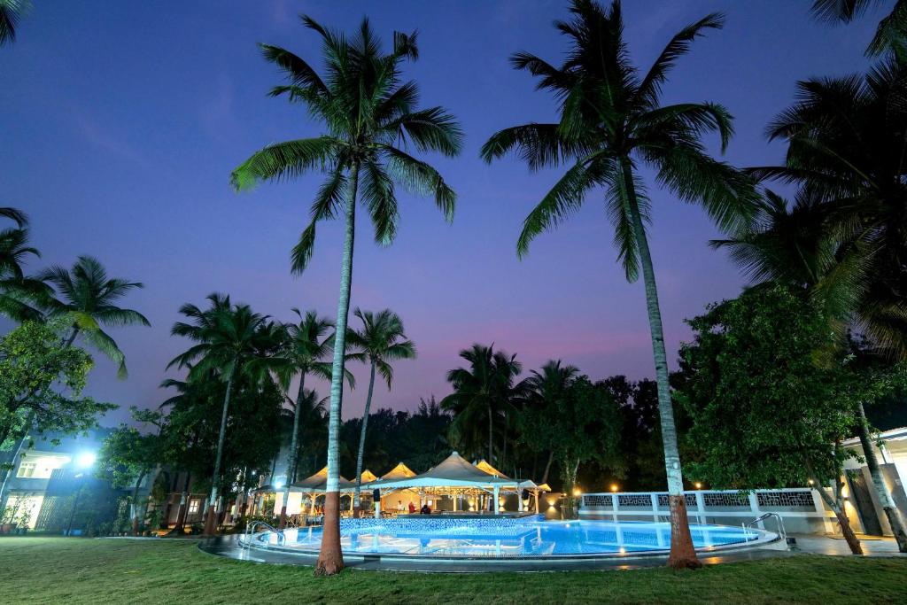 达曼Gold Beach Villa的夜间带游泳池和棕榈树的度假村