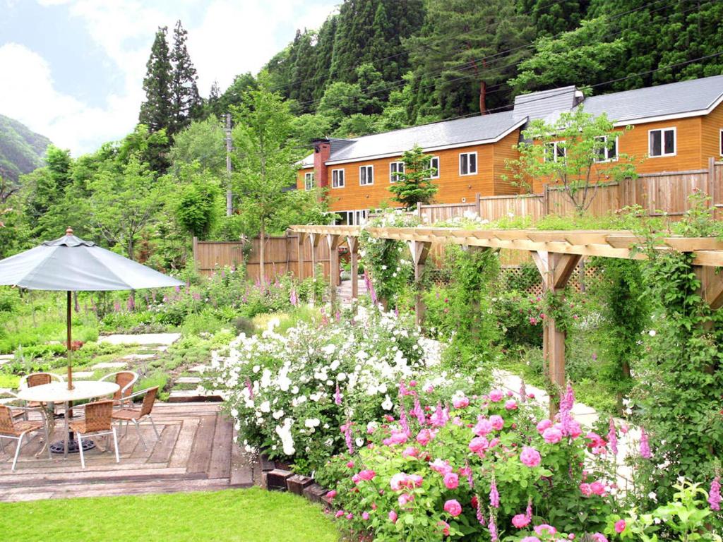 水上町阿萨内博旅馆的花园种有鲜花,设有桌子和雨伞