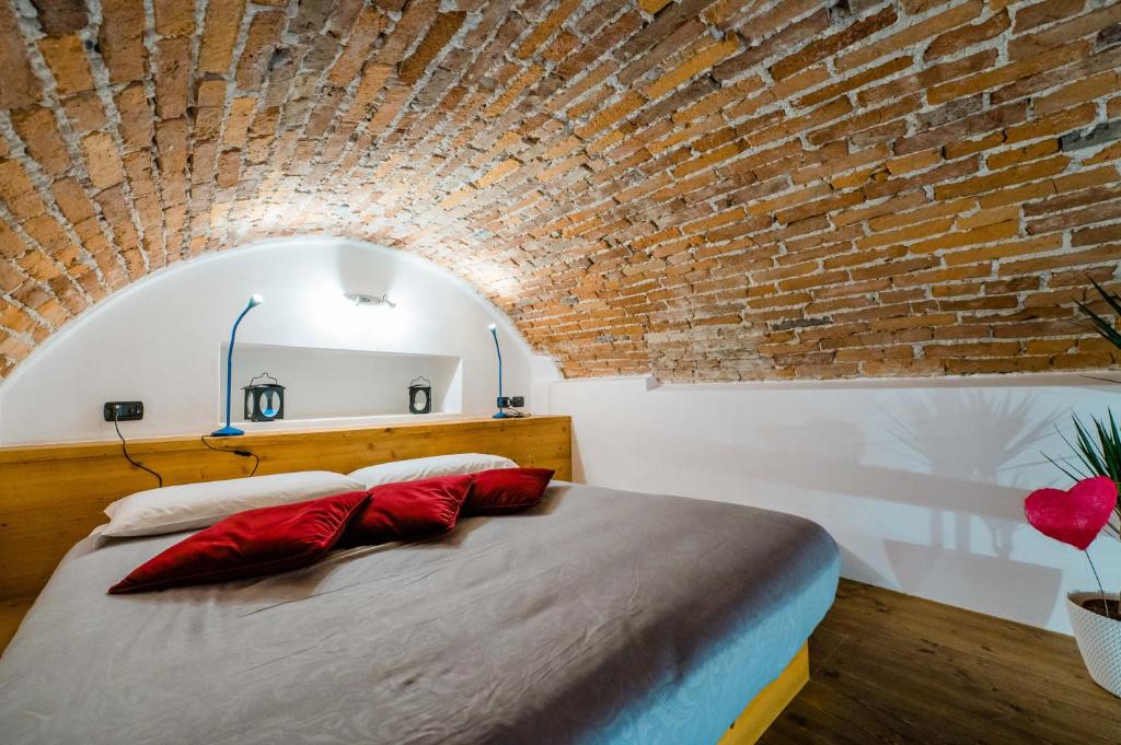 贝加莫FEEL - Sweet Old Town的一间卧室设有砖墙和一张带红色枕头的床