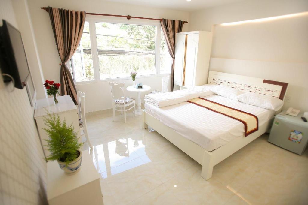 大叻Thanh Thanh Hotel的卧室配有白色的床和窗户。