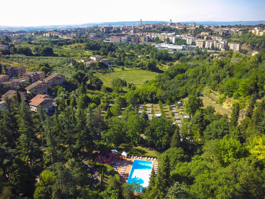 锡耶纳锡耶纳科勒维德露营酒店的享有带游泳池和树木的度假村的空中景致