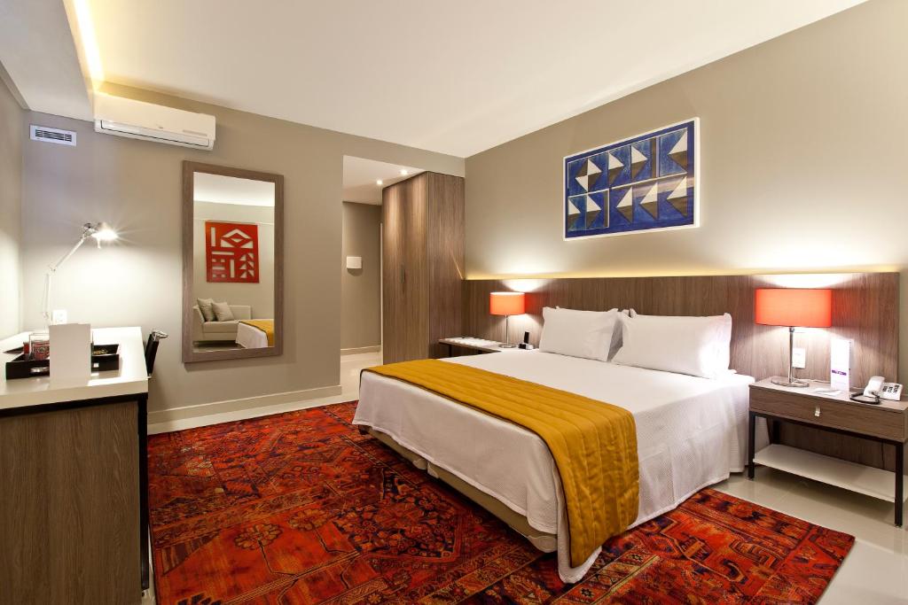 塞蒂拉瓜斯San Diego Suites Veredas Sete Lagoas的酒店客房设有一张大床和一张书桌。