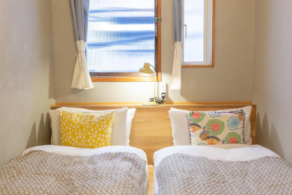 东京東京光明旅舍的一间设有两个靠垫和窗户的客房