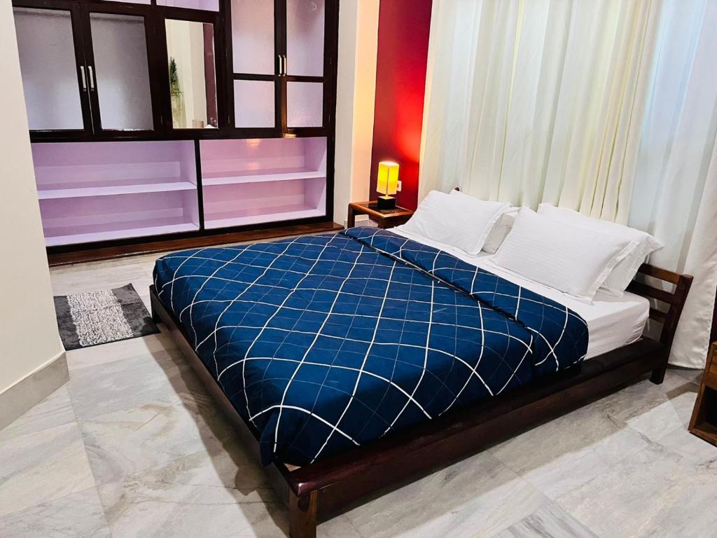 因帕尔JOY'S BNB的一间卧室配有一张带蓝色毯子的大床