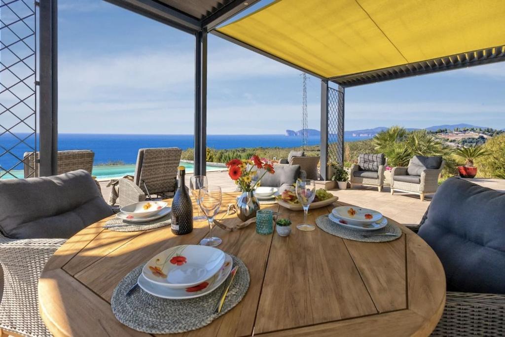 阿尔盖罗Villa Luxury Sunshine Alghero con piscina vista mare的海景木制餐桌