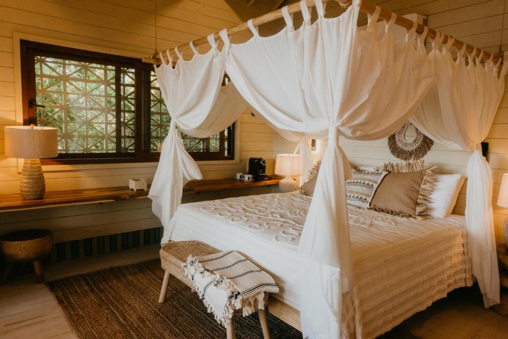 桑迪湾Tranquilseas Eco Lodge & Dive Center的一间卧室配有一张带天蓬的白色床