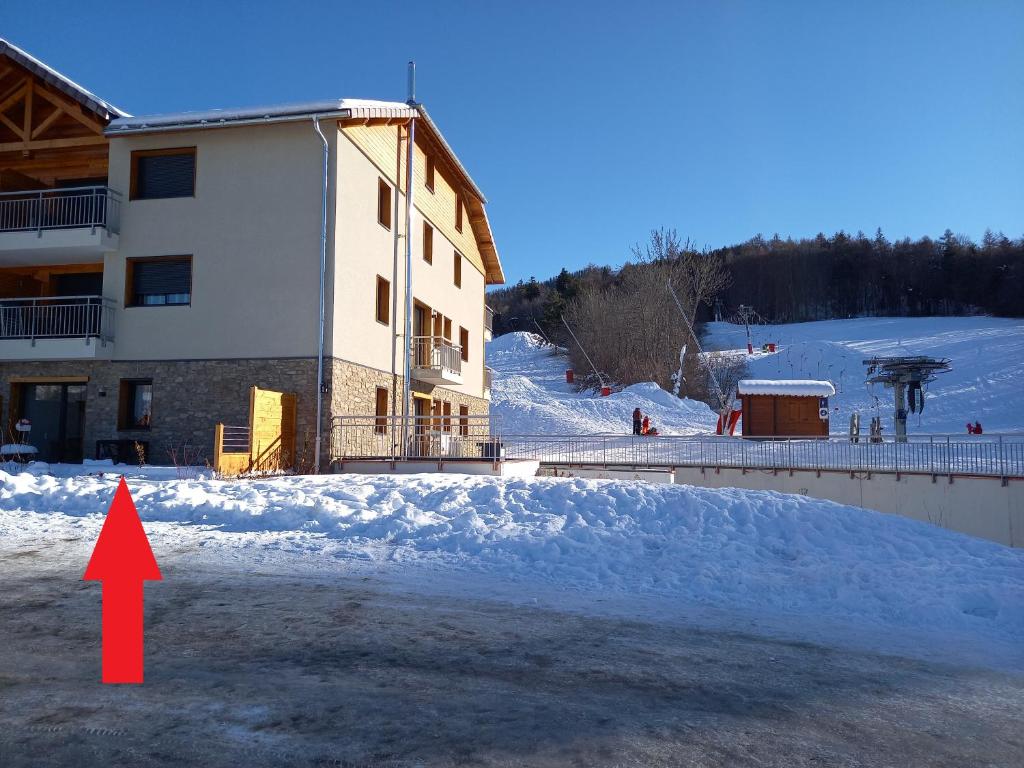 昂塞勒Appartement Les Vallons au pied des pistes的红箭指向雪中的建筑物