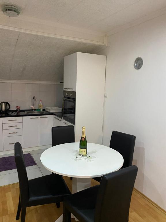 诺维萨德Apartmani Petra的白色的厨房配有白色的桌子和一瓶香槟