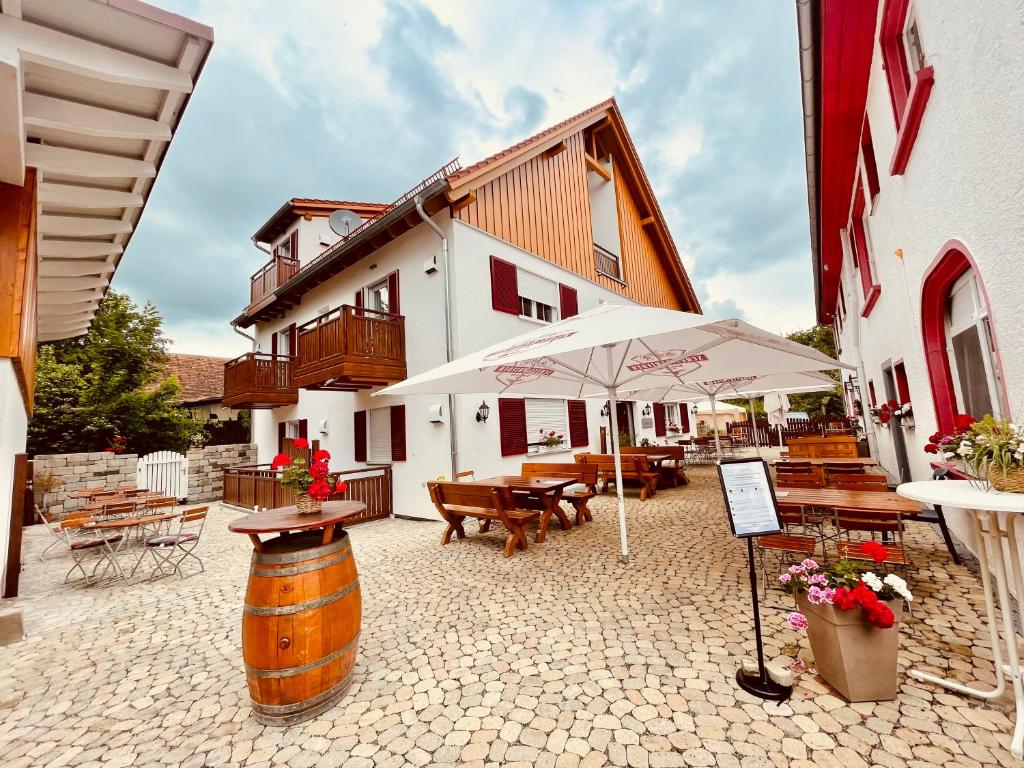 马克多夫Landgasthof Linde Hepbach, Hotel & Restaurant的一个带桌子和遮阳伞的庭院和一座建筑