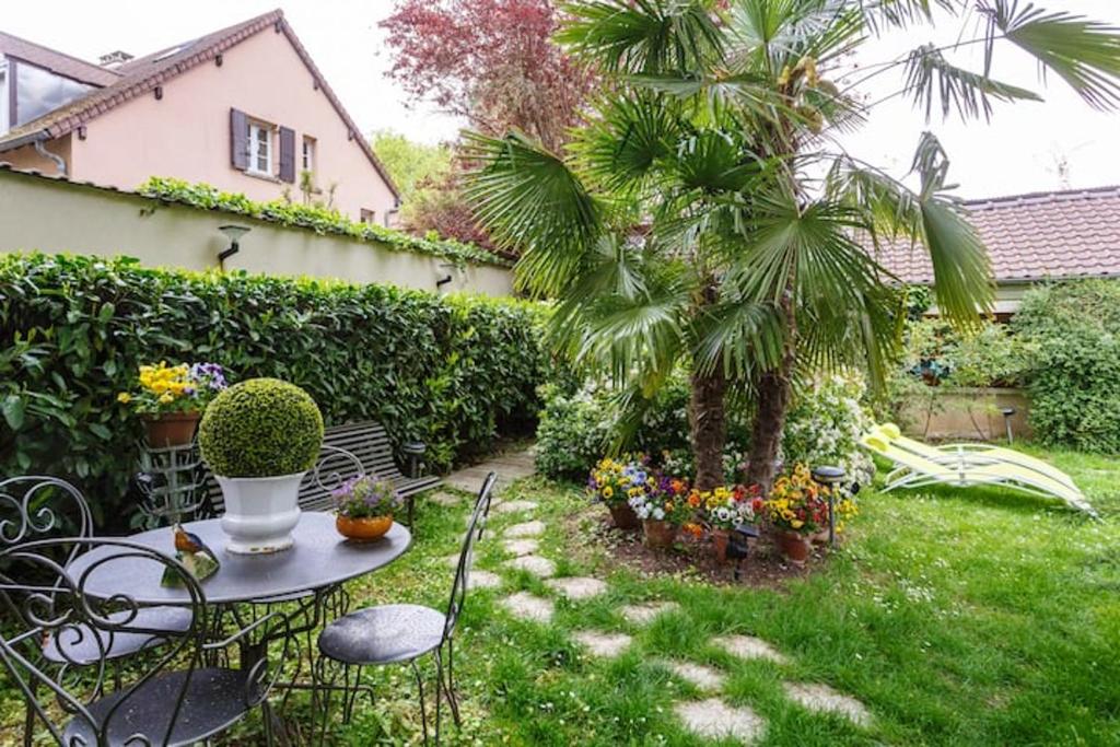 马恩河畔尚Studio avec jardin clos et wifi a Ville d'Avray a 1 km des pistes的一个带桌子和棕榈树的小花园