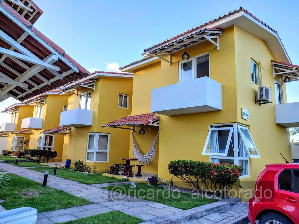 皮廷布Praia Bela Paraíba Casa 220的一座黄色的房子,前面有一辆红色的汽车