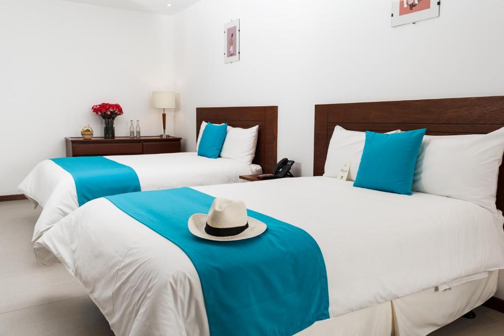 拉塔昆加REEC Latacunga by Oro Verde Hotels的床铺位于酒店客房,床上有一顶帽子