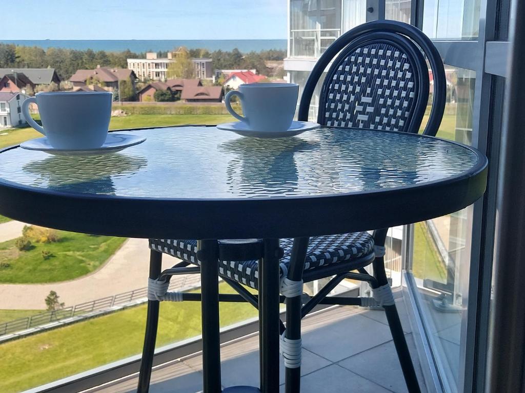 斯文托伊Apartamentai Elija su vaizdu į jūrą的窗前带两杯和两把椅子的桌子