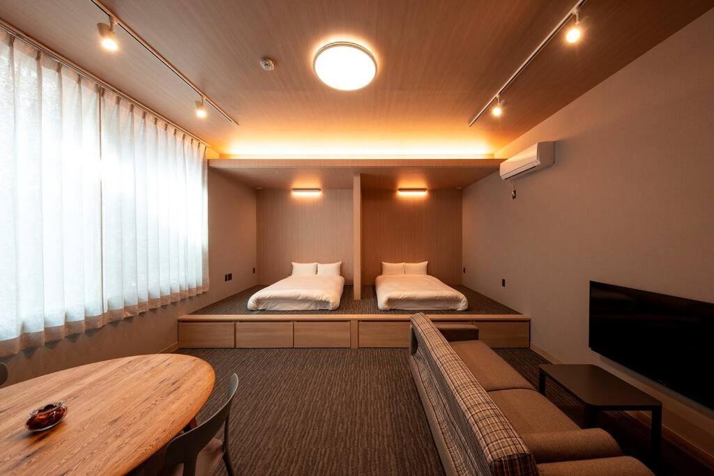 福冈White Crystal RoomA的客房设有两张床、一张桌子和一台电视机。