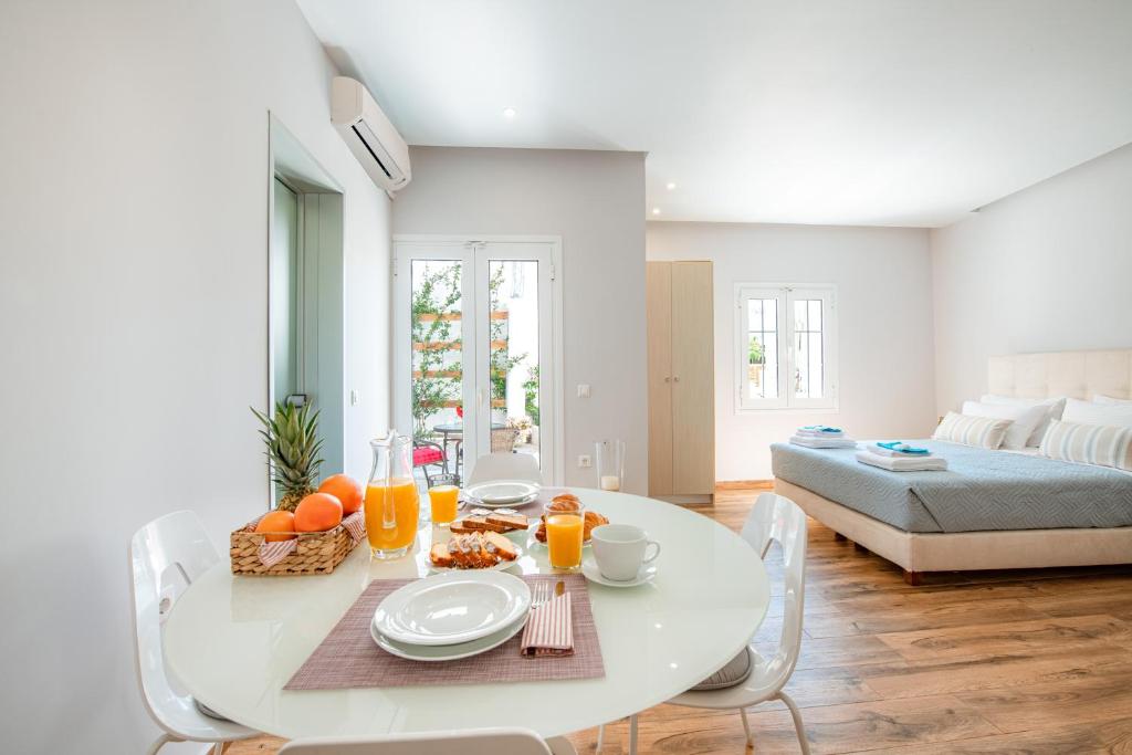 卡沃斯KORINA APART HOTEL KAVOS的一间白色的用餐室,配有一张桌子,提供食物和橙汁
