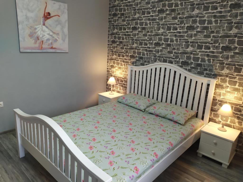瓦尔纳Aпартамент 5的卧室配有白色婴儿床、两个床头柜和砖墙