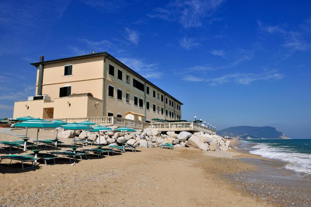 雷卡纳蒂港Hotel Brigantino Non Dista的海滩上的一座建筑,配有椅子和遮阳伞