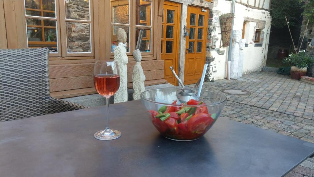 RaversbeurenFerienwohnung Kunstscheune Mosel的一杯葡萄酒和一碗水果放在桌子上