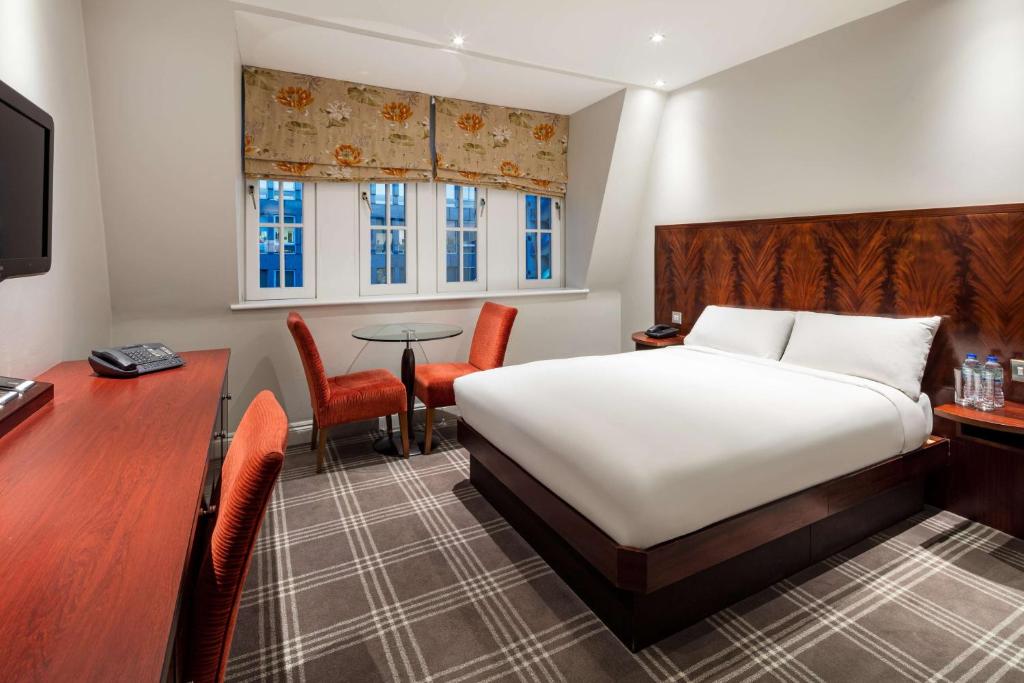 伦敦Radisson Blu Edwardian Grafton Hotel, London的配有一张床、一张桌子和一张桌子的酒店客房