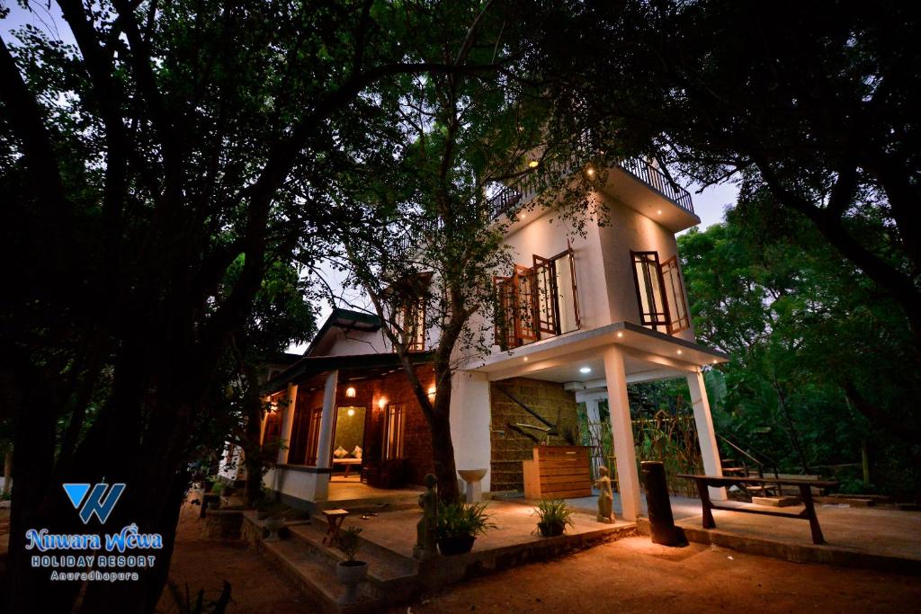 阿努拉德普勒Nuwara Wewa Holiday Resort的前面有一棵树的小白色房子