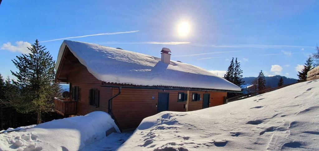 克利浦托尔Bergzeit Klippitz的雪覆盖的房子,后面有太阳