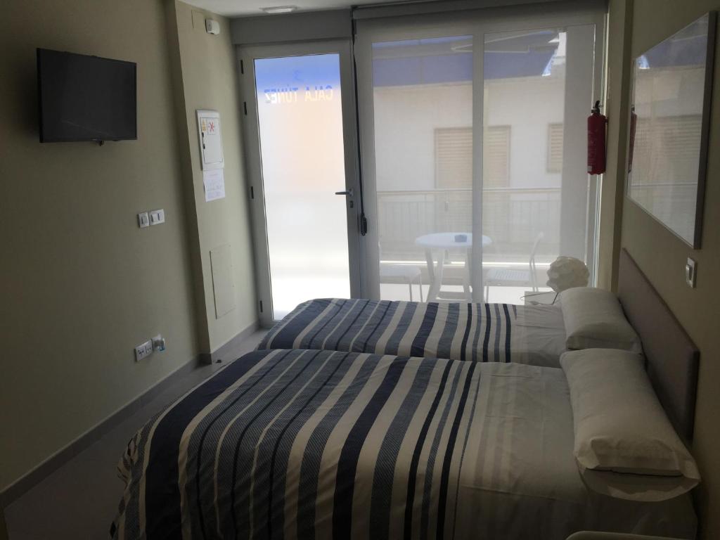 帕洛斯角Apartamentos Turisticos Maria Guerrero的一间卧室设有一张床和一个滑动玻璃门