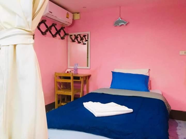 皮皮岛Sea Shell Hut的一间卧室配有一张蓝色的床和粉红色的墙壁