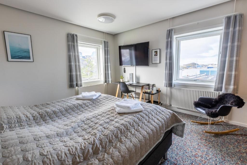 努克HOTEL SØMA Nuuk的一间卧室配有一张床、一把椅子和窗户。