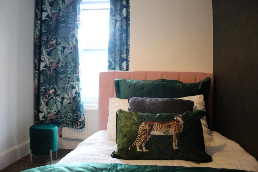 科尔切斯特The Velveteen Townhouse的卧室配有带枕头的床铺和窗户。