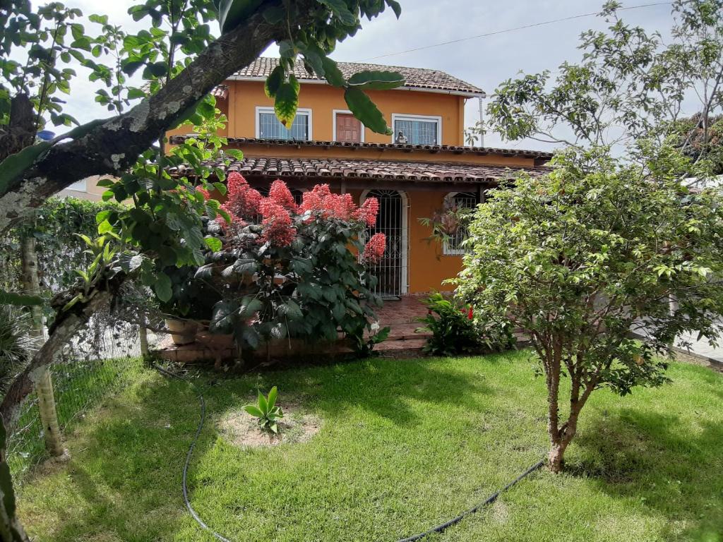 瓜拉派瑞Casa de praia em Guarapari - Santa Mônica.的院子里有红色花的房子