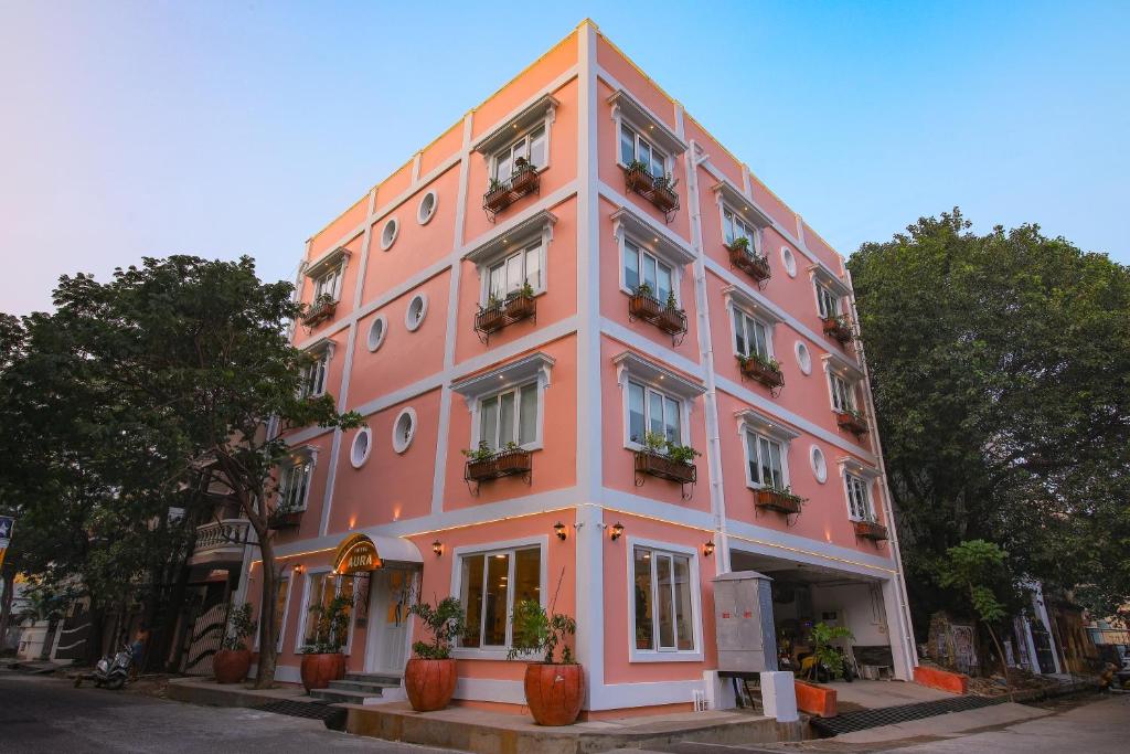 蓬蒂切里AURA HOTEL的前面有盆栽植物的粉红色建筑