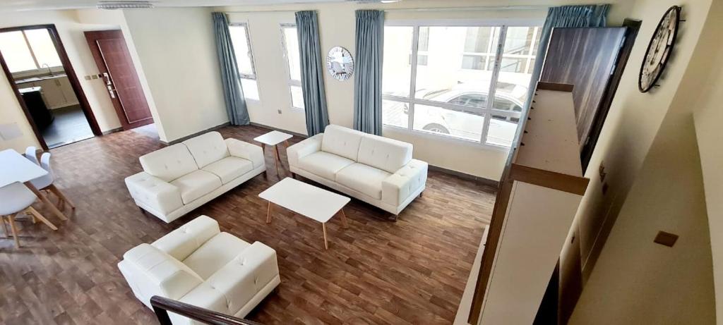 迪拜HAVANA HOLIDAY HOMES MIRDIF的客厅配有2把白色椅子和桌子
