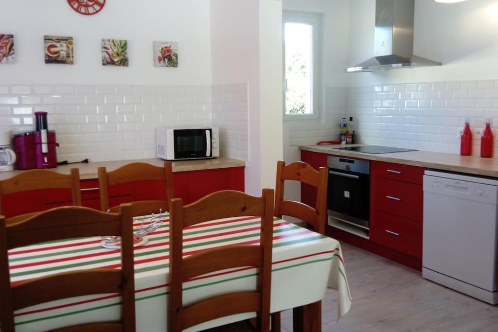 Uhart-Cizebaratzean的厨房配有红色橱柜和桌椅