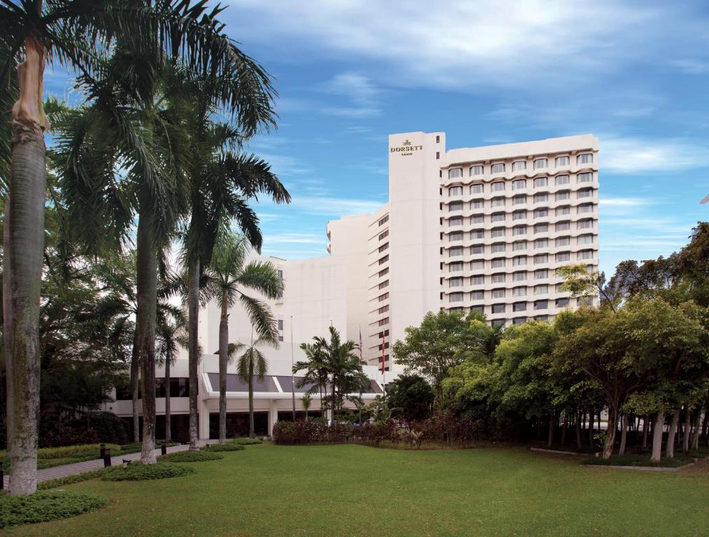 梳邦再也梳邦帝盛君豪酒店的一座种植了棕榈树和公园的大型白色建筑