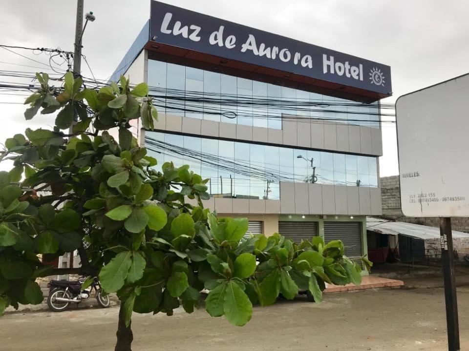 曼塔Luz de Aurora HOTEL的建筑物前有标志的树