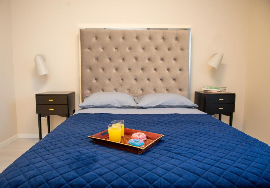 考纳斯Luxurious Blue&Yellow Apartment in Kaunas Center的床上的托盘,上面放着两只甜甜圈和橙汁