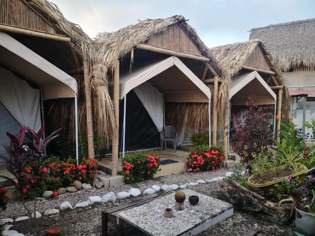 帕洛米诺El Nómada Hostel的一座带桌子和鲜花的茅草建筑的度假村