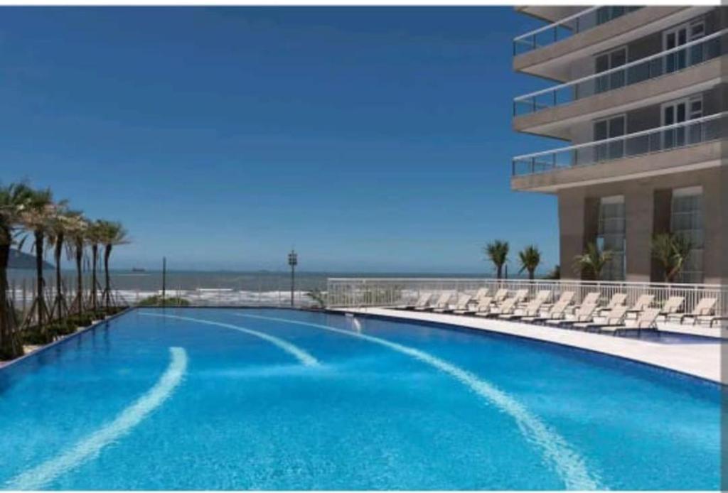 桑托斯Santos Unlimited 2 Dormitórios, 32o andar com vista Mar!的一座带椅子的大型游泳池和一座建筑