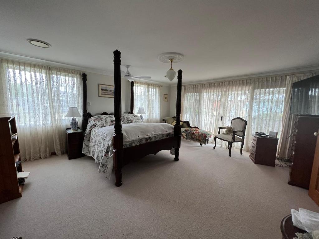 DeewhyLuxury 4 bedroom house的一间卧室配有一张床、一把椅子和窗户。