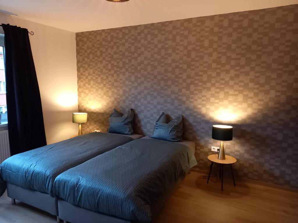埃姆登Ems Apartment的一间卧室配有一张带蓝色床单的床和两盏灯。