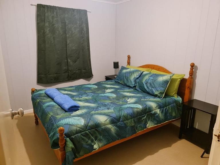 库伯佩迪City Centre Apartments的一间卧室配有一张带蓝色床单的床和一扇窗户。